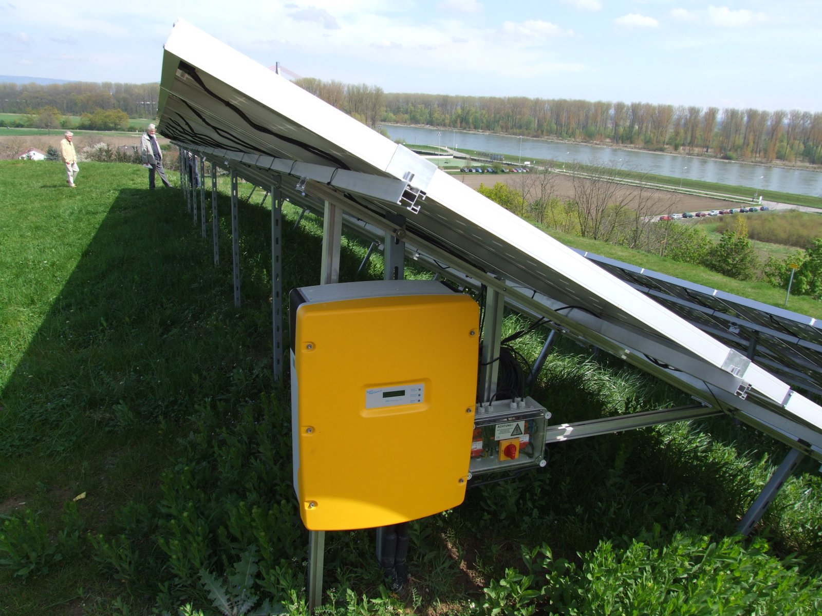 Wall-mounted solar inverter near an array, converting DC to AC.